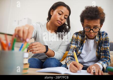 Low-Winkel-Porträt der modernen afrikanischen Frau helfen Sohn zu Hause studieren, Fernunterricht Konzept Stockfoto