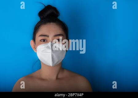 Nahaufnahme der jungen Asienfrau, die eine medizinische Maske n95 aufsetzt, um vor Atemwegserkrankungen wie der Grippe-covid-19 PM2.5 Staub und Smog bei BL zu schützen Stockfoto