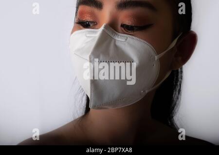 Nahaufnahme der jungen Asienfrau, die eine medizinische Maske n95 aufsetzt, um vor Atemwegserkrankungen wie der Grippe-covid-19 PM2.5 Staub und Smog bei gr Stockfoto