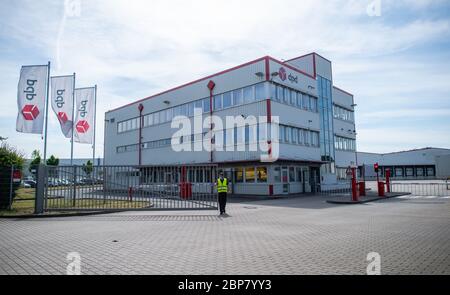 18. Mai 2020, Nordrhein-Westfalen, Hückelhoven-Hilfarth: Ein Mitarbeiter mit einer Warnweste schließt das Tor am Standort des Paketzustellers DPD. Der Paketzusteller DPD hat seinen Standort in Hückelhoven im Kreis Heinsberg mit 400 Mitarbeitern aufgrund eines Corona-Ausbruchs vorübergehend geschlossen. Foto: Jonas Güttler/dpa Stockfoto