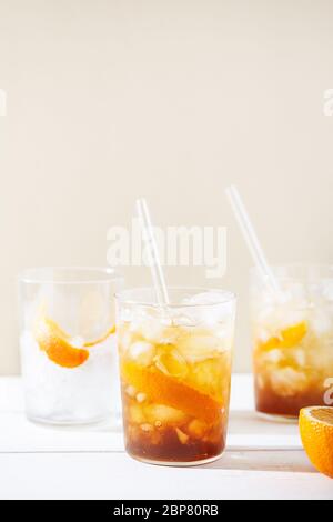 Erfrischende Erfrischungsgetränke, darunter ein kalter Kaffee-Cocktail und ein Zitrusfrüchte-Espresso-Tonic, mit Orangenschale und Glasstrohhalmen dekoriert Stockfoto