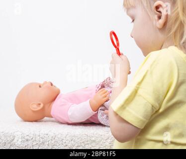 Kleines Mädchen behandelt eine Puppe ihr Spielzeug. Das Konzept der pädiatrischen Onkologie und Immunologie Medizin, Kinderchirurgie Stockfoto