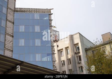 Ein Mann isoliert die Wände eines Gebäudes mit einer modernen, belüfteten Fassade. Das Konzept der Frostbeständigkeit und Schalldämmung Stockfoto