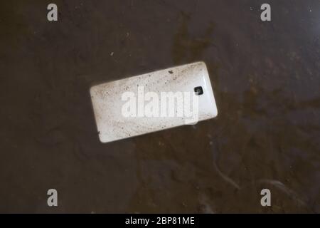 Handy liegt auf dem Bürgersteig in der Pfütze Stockfoto
