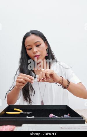 Kreative Mixed-Race-Frau, die schöne Naturstein Ohrringe für den Kunden Stockfoto