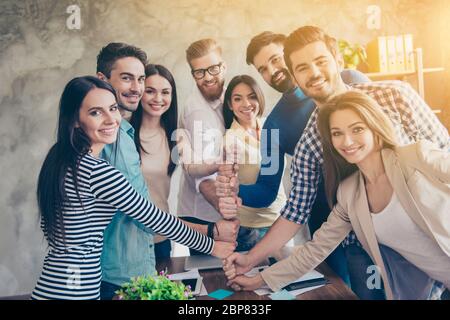 Konzeption des erfolgreichen Teambuilding. Nahaufnahme von Geschäftsleuten, die ihre Fäuste auf dem Schreibtisch in einem schönen, leichten Arbeitsplatz übereinander legen, Stockfoto