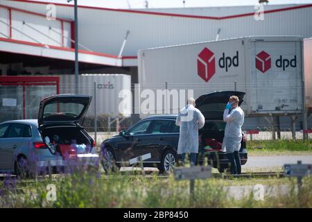 18. Mai 2020, Nordrhein-Westfalen, Hückelhoven-Hilfarth: Zwei Mitarbeiter eines Desinfektionsdienstes setzen ihre Schutzausrüstung auf dem Parkplatz des Paketzustellers DPD auf. Das Logistikunternehmen hat seinen Standort in Hückelhoven im Kreis Heinsberg mit 400 Mitarbeitern aufgrund eines Corona-Ausbruchs vorübergehend geschlossen. Foto: Jonas Güttler/dpa Stockfoto