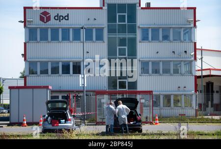 18. Mai 2020, Nordrhein-Westfalen, Hückelhoven-Hilfarth: Zwei Mitarbeiter eines Desinfektionsdienstes setzen ihre Schutzausrüstung auf dem Parkplatz des Paketzustellers DPD auf. Das Logistikunternehmen hat seinen Standort in Hückelhoven im Kreis Heinsberg mit 400 Mitarbeitern aufgrund eines Corona-Ausbruchs vorübergehend geschlossen. Foto: Jonas Güttler/dpa Stockfoto