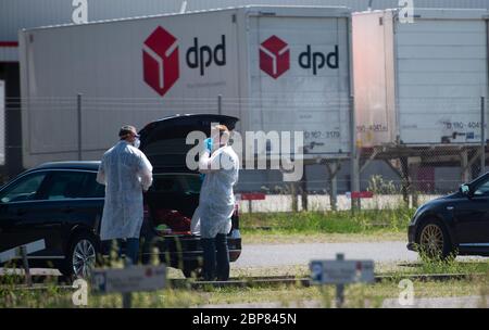18. Mai 2020, Nordrhein-Westfalen, Hückelhoven-Hilfarth: Zwei Mitarbeiter eines Desinfektionsdienstes setzen ihre Schutzausrüstung auf dem Parkplatz des Paketzustellers DPD auf. Das Logistikunternehmen hat seinen Standort in Hückelhoven im Kreis Heinsberg mit 400 Mitarbeitern aufgrund eines Corona-Ausbruchs vorübergehend geschlossen. Foto: Jonas Güttler/dpa Stockfoto