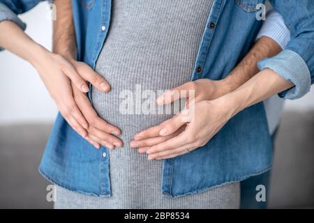 Nahaufnahme Bild von männlichen Händen berühren Womans schwanger Bauch Stockfoto