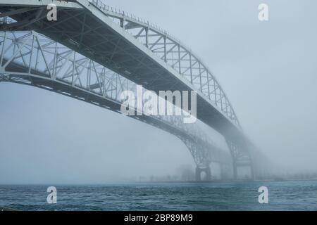 Nebel umschließt zwei Brücken über dem Fluss. Pfad, der in eine unbekannte Zukunft führt, aus dem Nebel zu kommen. Stockfoto