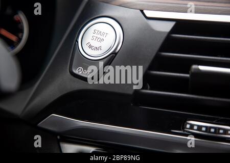 Nahaufnahme eines Start-Stopp-Knopfes auf einem Armaturenbrett in einem modernen Premium-Luxusauto. Nahaufnahme, Weichstellung. Stockfoto