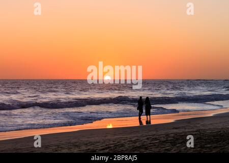 Ein Paar beobachtet den Sonnenuntergang am Strand von Maspalomas, Gran Canaria, Kanarische Inseln, Spanien Stockfoto