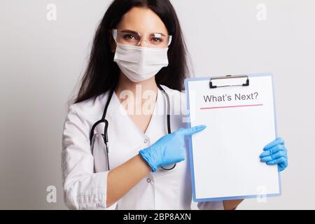 Arzt in Handschuhen, Maske und Brille hält Blatt mit Text, was als nächstes kommt Stockfoto