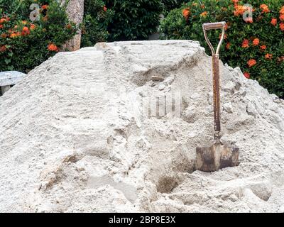 Alte rostige Schaufel im Sandhaufen auf grünen Blättern Hintergrund. Stockfoto