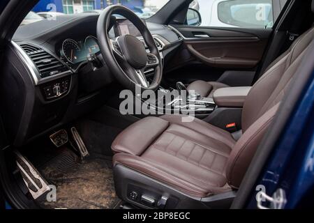 Leeres Interieur des modernen Premium-Serienwagens. Fahrersitz aus braunem Leder. Schmutziges Interieur, Teppiche im Schlamm. Nahaufnahme, weiche Fokussierung Stockfoto