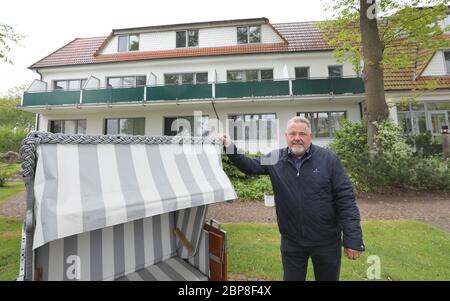 18. Mai 2020, Mecklenburg-Vorpommern, Graal-Müritz: Detlef Nippkow, Inhaber der Pension "Haus am Meer", steht vor seinem Hotel neben einem Liegestuhl. Das Haus am Meer ist nach einer einwöchigen Pflichtpause durch Corona heute wieder für Gäste aus Mecklenburg-Vorpommern und ab 25.05.2020 für Besucher aus ganz Deutschland geöffnet. Nippkow befürchtet, dass die Krise des Coronavirus die Tourismusbranche noch viele Jahre beschäftigen wird. Foto: Bernd Wüstneck/dpa-Zentralbild/dpa Stockfoto