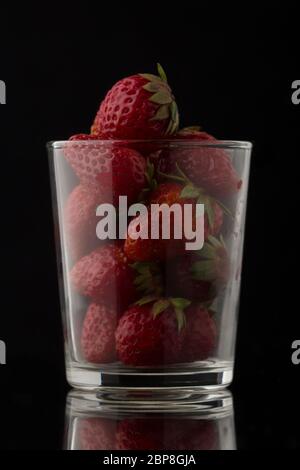 Köstliche frische und reife Erdbeeren in einem transparenten Glas auf schwarzem Hintergrund Stockfoto