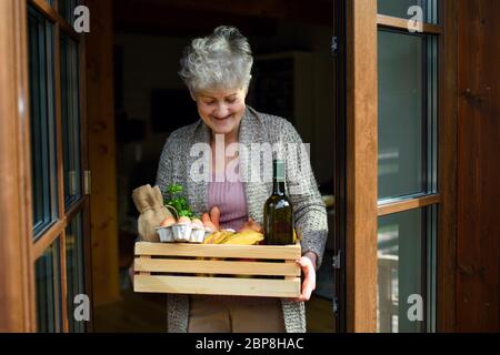 Vorderansicht der Frau, die die Lieferung von Lebensmitteln vor der Haustür hält. Stockfoto