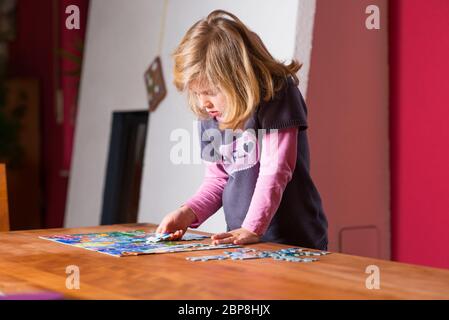 Kleine blonde Mädchen tun ein Puzzle Stockfoto