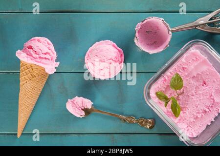 Ansicht von oben Rosa Eis Waffelhörnchen mit Utensil auf blauem rustikalen hölzernen Hintergrund. Stockfoto