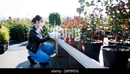 Junge Frau mit Gesichtsmaske im Freien Einkaufen im Garten Zentrum, Corona Virus Konzept. Stockfoto