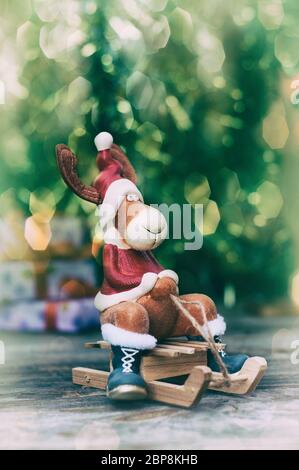 Weihnachten Elch in Kleidung auf hölzernen Schlitten, verschwommenen Hintergrund mit großen Bokeh, vintage Toning Stockfoto