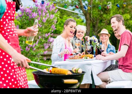 Man Grillen von Fleisch und Gemüse auf Garden Party, seine Freunde Essen der BBQ-Fleisch Stockfoto