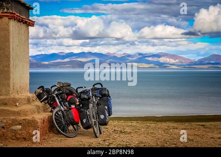 Zwei Radwandern geladen Fahrräder an der Wand eines kleinen alten tibetischen Kloster auf einem Hügel über dem heiligen See Manasarovar, Tibet, China ruhte Stockfoto