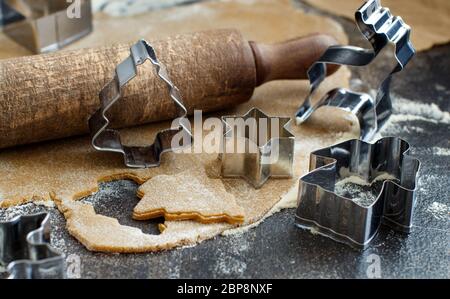 Kochen Weihnachtsplätzchen mit Ausstecher auf einen dunklen Tisch Stockfoto