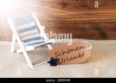 Sonnigen Sommer Label mit Sand und Alter Holz- Hintergrund. Deutsche Text schoenen Urlaub bedeutet frohe Feiertage. Liegestuhl für den Urlaub oder die Ferien Gefühl. Stockfoto