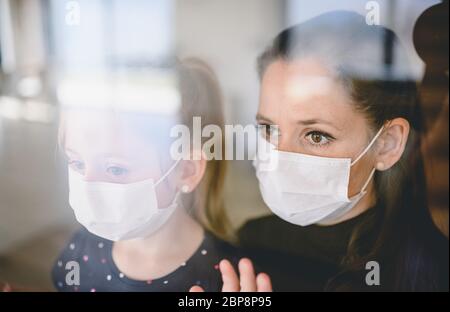 Mutter und Kind mit Gesichtsmasken zuhause, Corona-Virus und Quarantäne-Konzept. Stockfoto