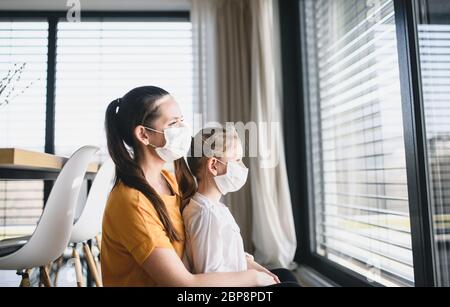 Mutter und Kind mit Gesichtsmasken zuhause, Corona-Virus und Quarantäne-Konzept. Stockfoto