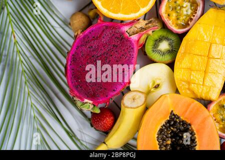 Exotische tropische Früchte. Papaya, Mango, Drachenfrucht, Passionsfrucht, Kiwi, Erdbeere, apfel, Banane, Kiwi, grüne Blätter auf weißem Hintergrund. An Stockfoto