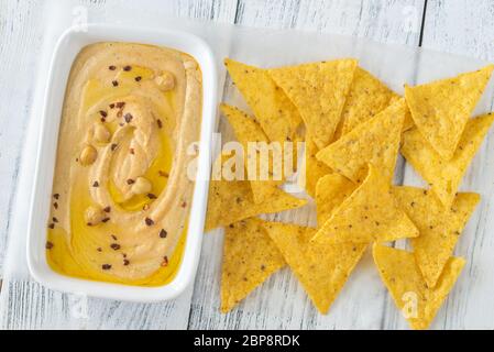 Schüssel mit Hummus mit Tortilla Chips auf dem hölzernen Tisch Stockfoto