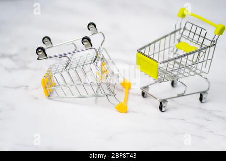 Nahaufnahme von zwei leeren Metall kleine Miniatur-Spielzeug-Shopping-Trolley auf weißem Hintergrund. Einkaufen, Supermarkt, Verkauf Konzept. Sammlung von Warenkörben Stockfoto