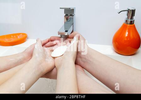 Kinder waschen Hände mit Seife unter dem Kran mit Wasser. Nahaufnahme. Körperhygiene-Konzept Stockfoto