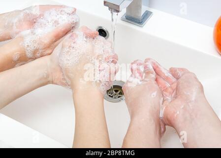 Kinder waschen Hände mit Seife unter dem Kran mit Wasser. Nahaufnahme. Körperhygiene-Konzept Stockfoto