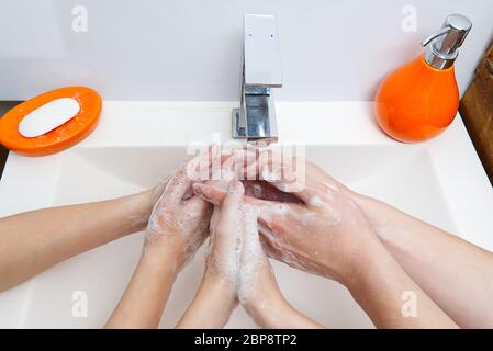 Kinder waschen Hände mit Seife unter dem Kran mit Wasser. Nahaufnahme. Körperhygiene-Konzept Stockfoto