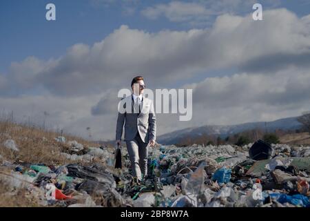 Moderner Geschäftsmann auf Deponien, Konsum versus Umweltverschmutzung Konzept. Stockfoto