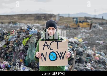 Frau Aktivistin mit Plakat Plakat auf Deponie, Umweltverschmutzung Konzept. Stockfoto