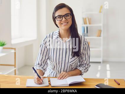 Hispanische Lehrerin mit Brille, die lächelnd die Kamera anschaut. Ein Hochschullehrer unterrichtet Remote mit einem Videoanruf-Anwendung Gadget. Stockfoto