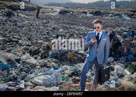 Moderner Geschäftsmann auf Deponien, Konsum versus Umweltverschmutzung Konzept. Stockfoto