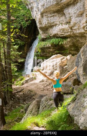 Aktive Frau Anheben der Arme das Einatmen frischer Luft, Gefühl, entspannt und frei in schöner natürlicher Umgebung unter Wasserfall Pericnik in Vrata Tal in Tr Stockfoto