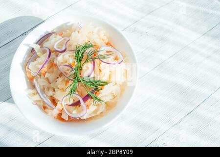 Traditionelles Sauerkraut mit Dill und Zwiebeln in einer weißen Tasse. Das Konzept der richtigen Ernährung. Natürliches Probiotikum. Selektiver Fokus, Platz für Text Stockfoto