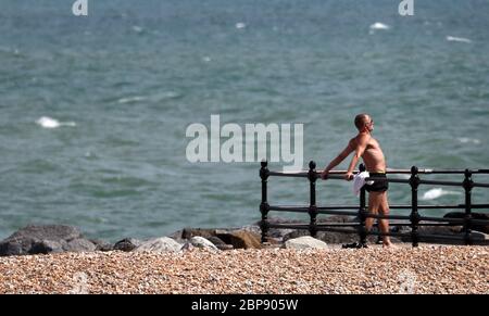 Ein Mann entspannt sich in der Sonne am Strand in Folkestone, Kent. Stockfoto