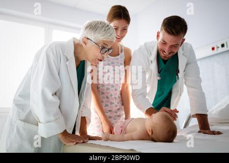 Glückliche schöne Mutter und kleines Baby auf ärztliche Untersuchung in Kinderarztpraxis Stockfoto