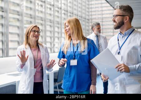 Gruppe von Ärzten, die auf einer medizinischen Konferenz im Korridor spazieren. Stockfoto