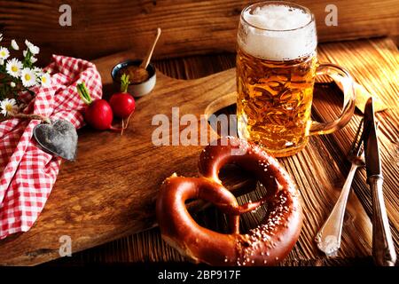 Bayerische Spezialitäten mit frischem Bier und Salzbrezel auf rustikalem Holz Stockfoto