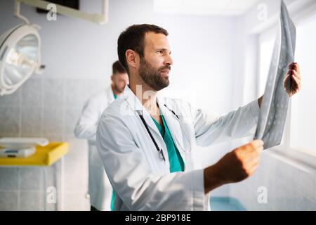 Porträt des jungen Arztes, der Röntgenaufnahmen im Krankenhaus überprüft, um eine Diagnose zu stellen Stockfoto